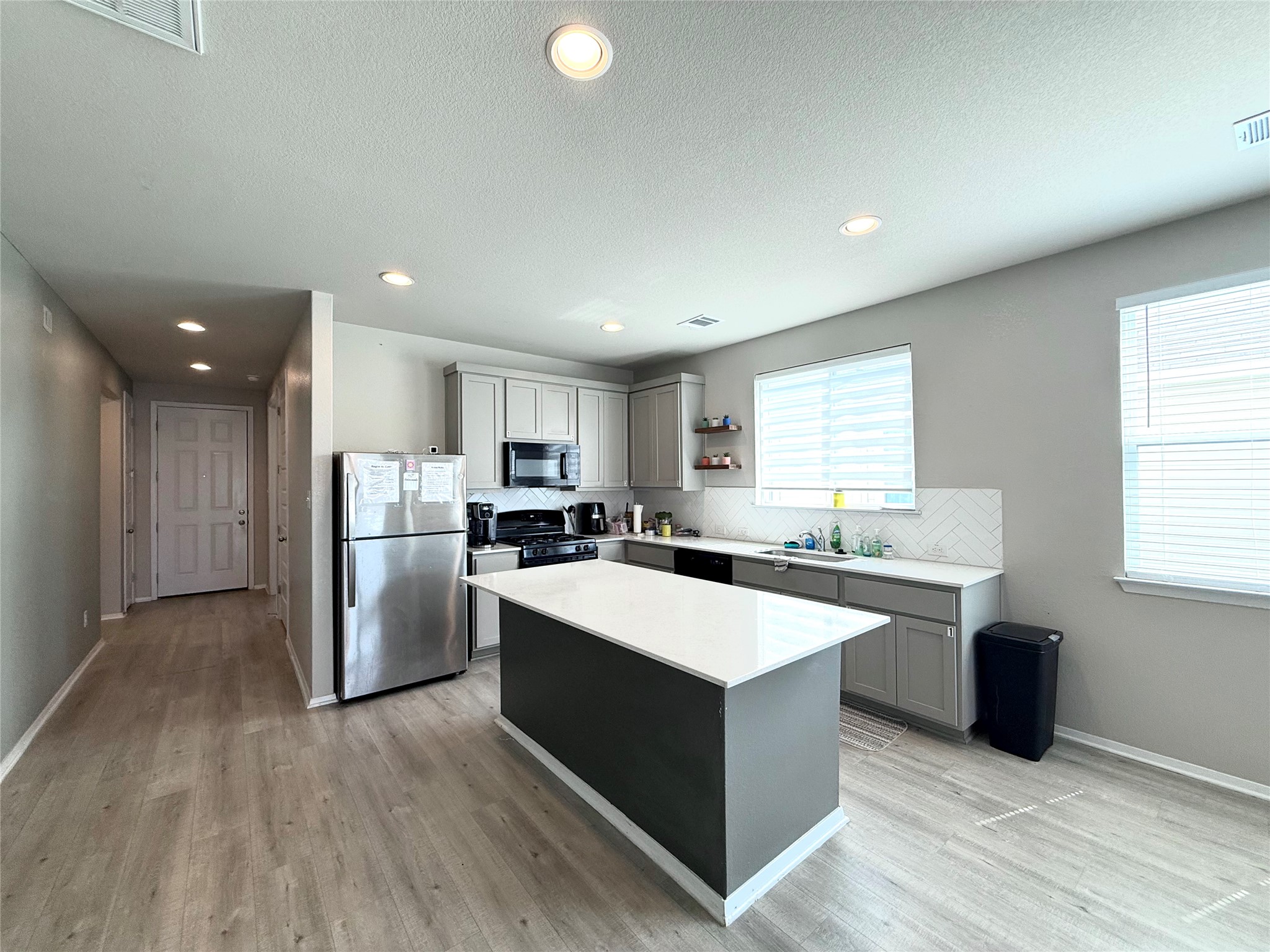 133 Fabion Street Kyle, TX 78640 - Photo 6 of 17 a large kitchen with stainless steel appliances a sink a refrigerator and a stove top oven with wooden floor
