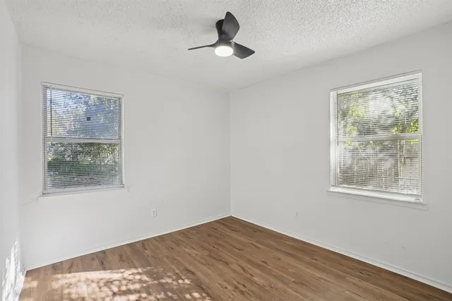 a wooden floor in an empty room with a window