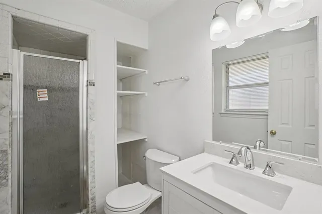 a bathroom with a sink a toilet and shower