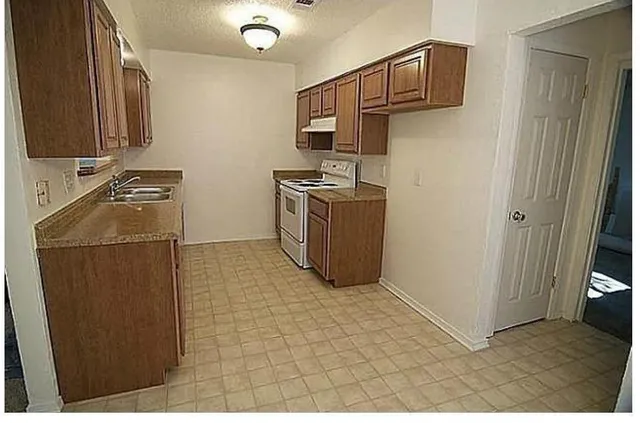a kitchen with stainless steel appliances granite countertop a refrigerator a stove and a sink