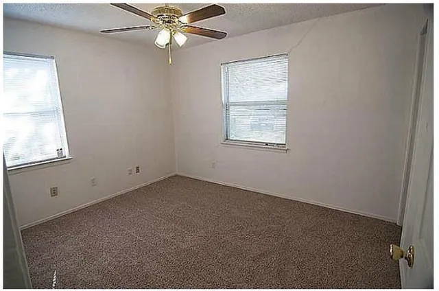 an empty room with a window and a fan