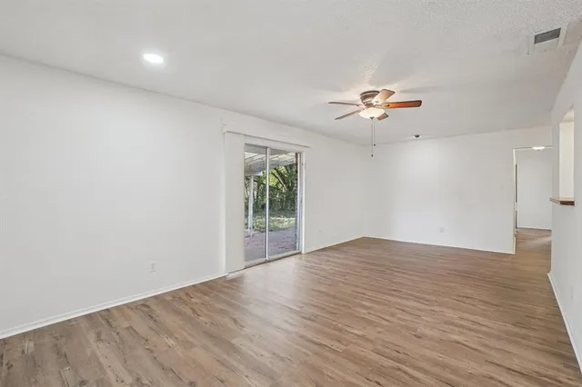 a view of an empty room with a window and wooden floor