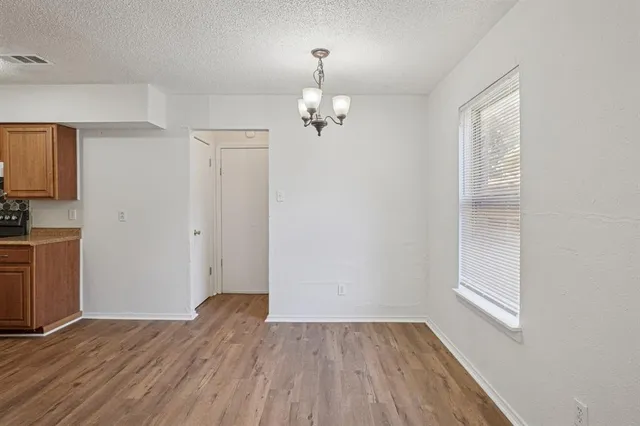 an empty room with wooden floor cabinet and windows