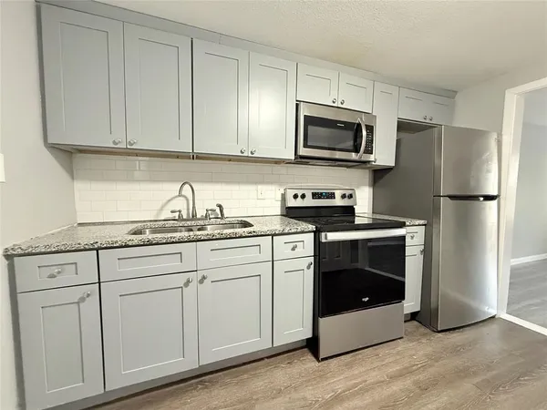 a kitchen with granite countertop white cabinets and stainless steel appliances