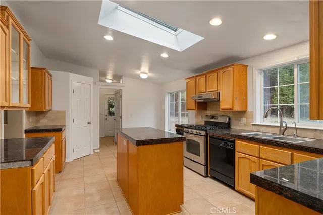 a kitchen with stainless steel appliances granite countertop a stove top oven a sink dishwasher a dining table and chairs with wooden floor