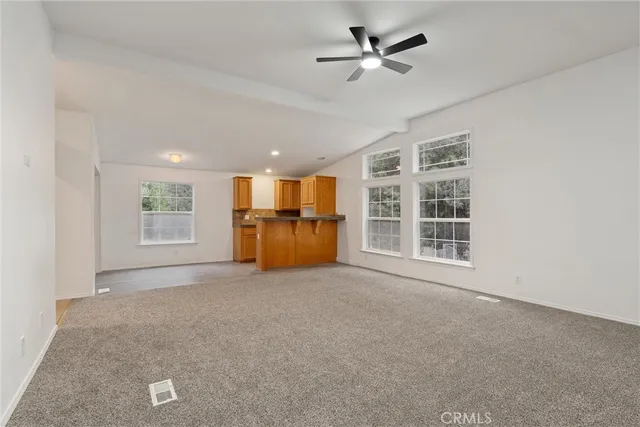 a view of an empty room with a window and kitchen view