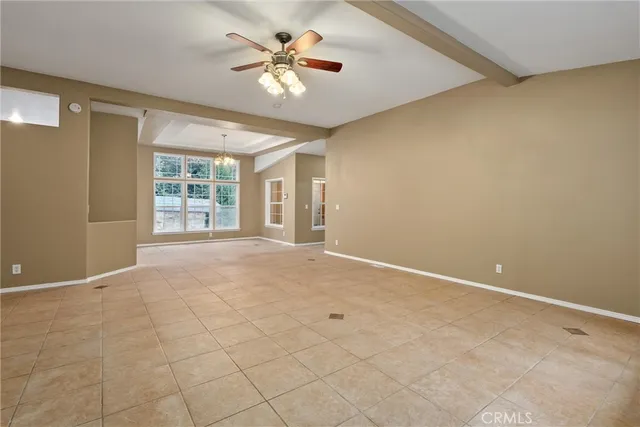 an empty room with windows and chandelier fan