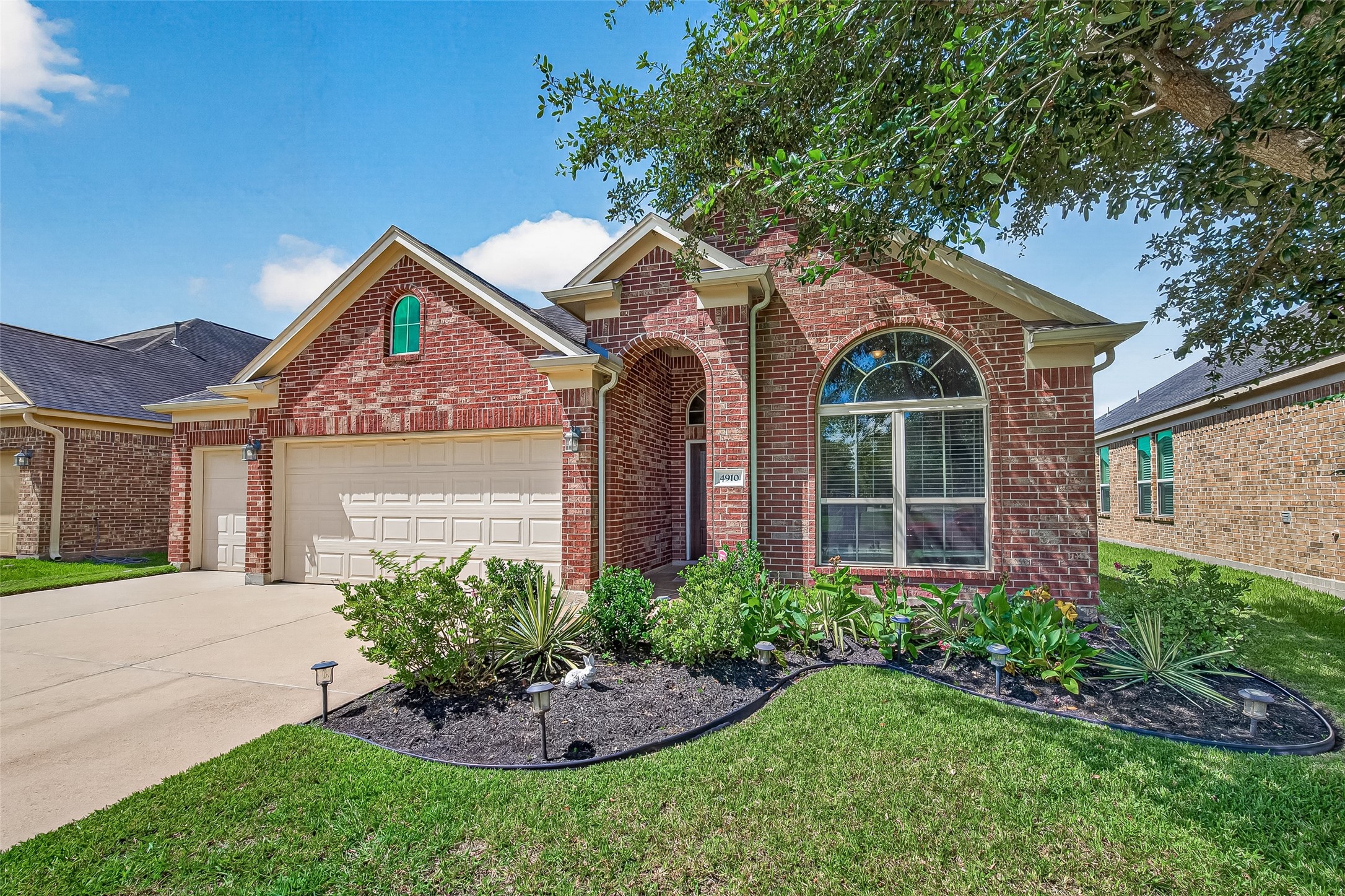 4910 Culver Lane Rosenberg, TX 77471 - Photo 1 of 50 Charming brick home with arched windows and a well-maintained front yard. Features a three-car garage, lush landscaping, and a welcoming entryway.