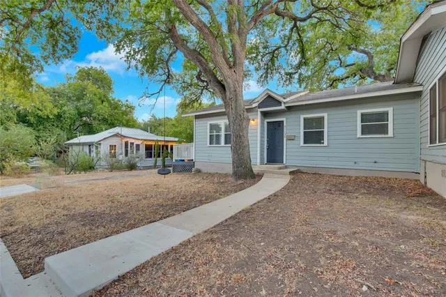 a view of a house with a yard and large tree