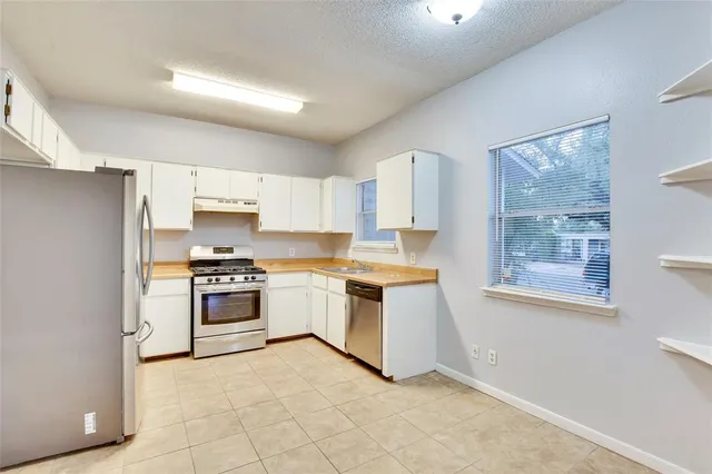 a kitchen with white cabinets and appliances