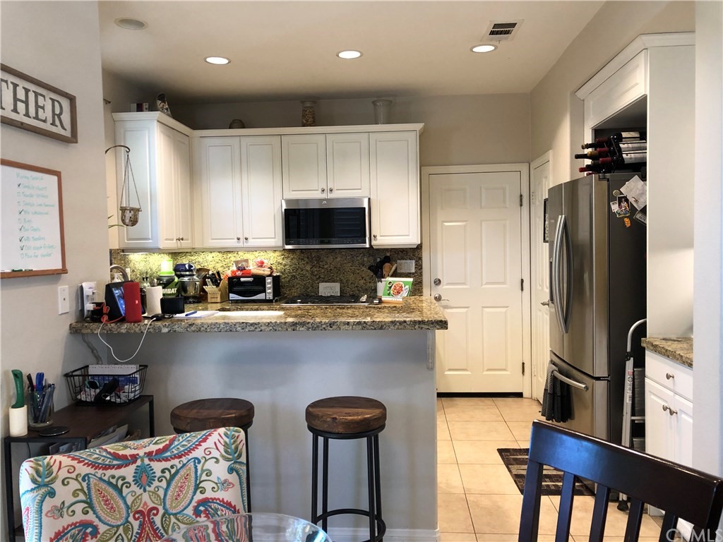 303 Canoe Pond Costa Mesa, CA 92627 - Photo 7 of 49 a kitchen with stainless steel appliances granite countertop a sink refrigerator and microwave