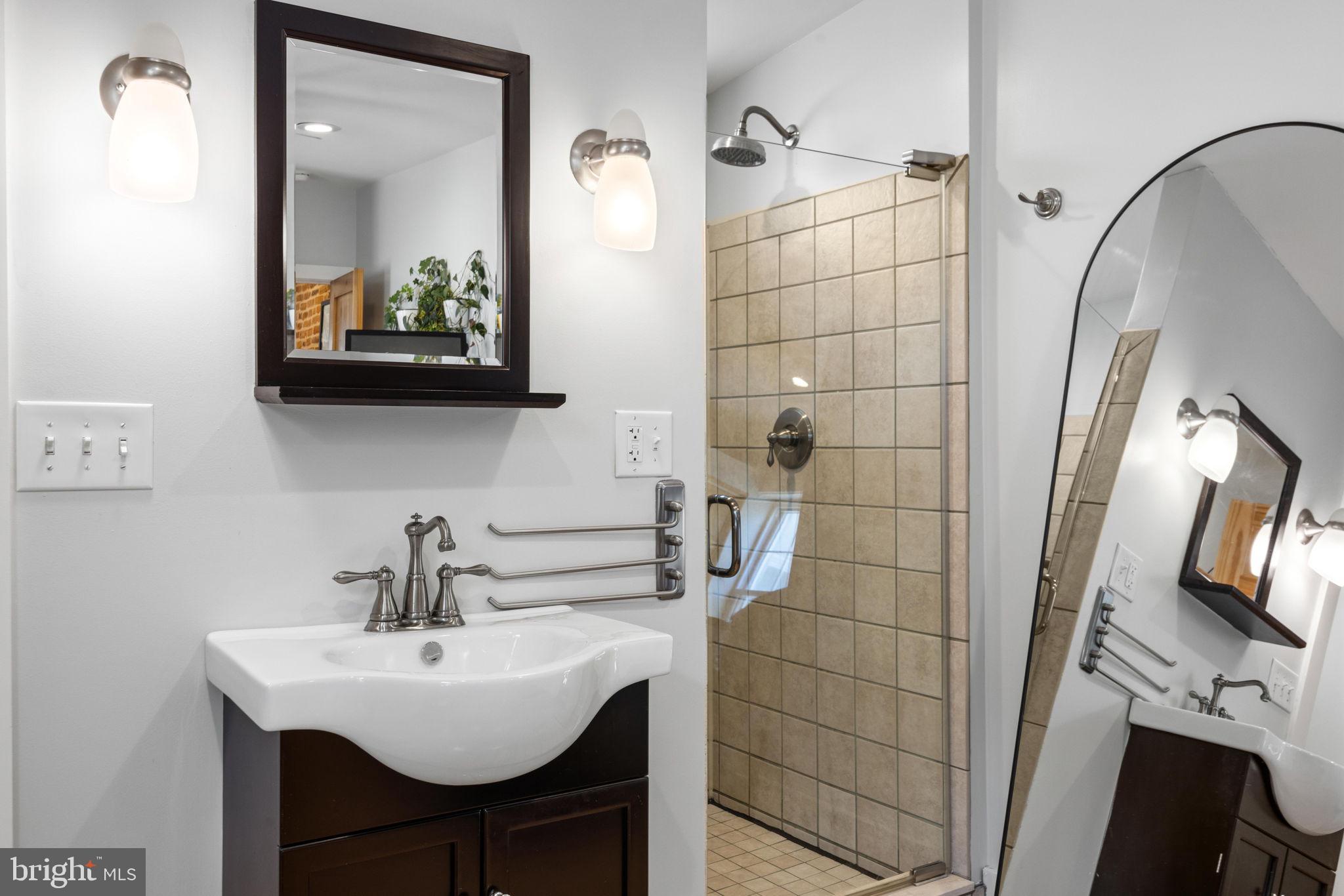 3208 Elliott Street Baltimore, MD 21224 - Photo 31 of 42 a bathroom with a sink a mirror and shower
