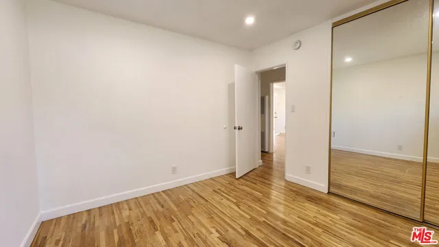 a view of an empty room with wooden floor and a bathroom