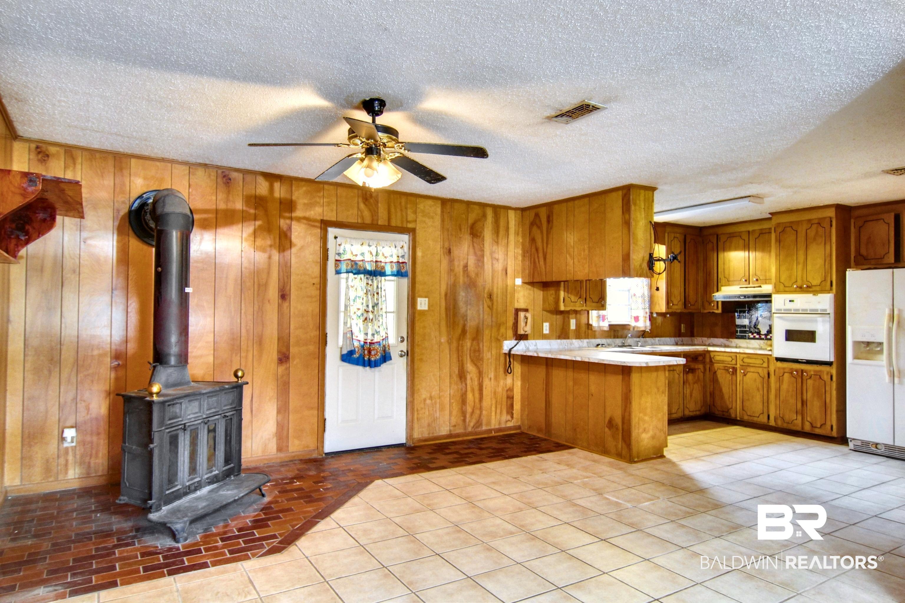 12897 County Road 65 Foley, AL 36535 - Photo 3 of 21 Kitchen with light countertops, white appliances, a ceiling fan, a peninsula, and brown cabinets
