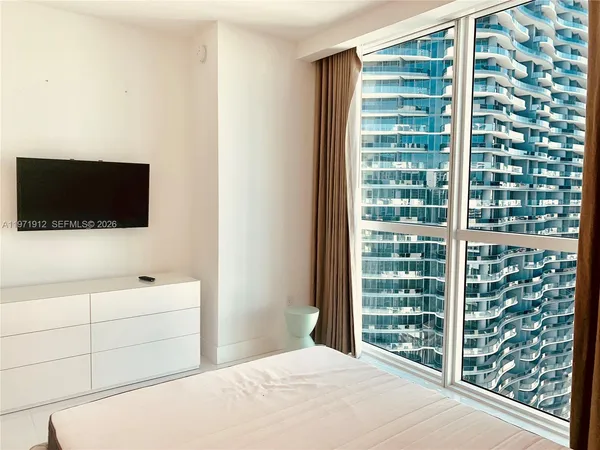 a bedroom with a bed and a flat tv screen in it