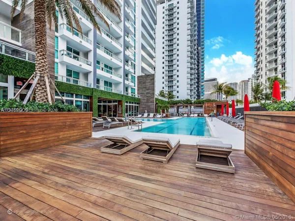 a swimming pool with outdoor seating and yard in front of it