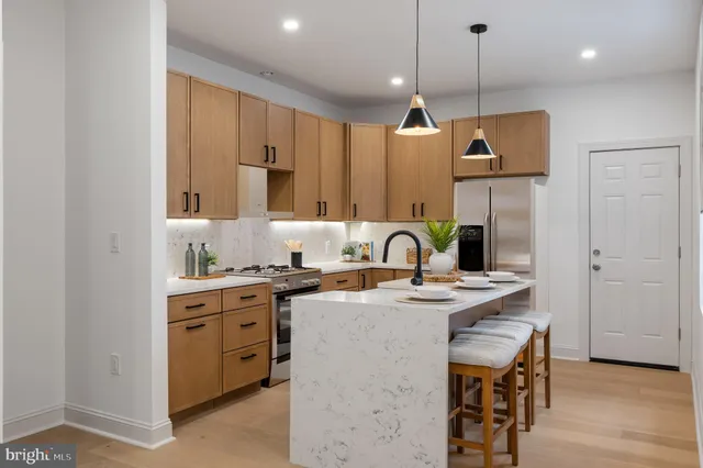 a kitchen with stainless steel appliances granite countertop a stove a sink a refrigerator and a wooden cabinets