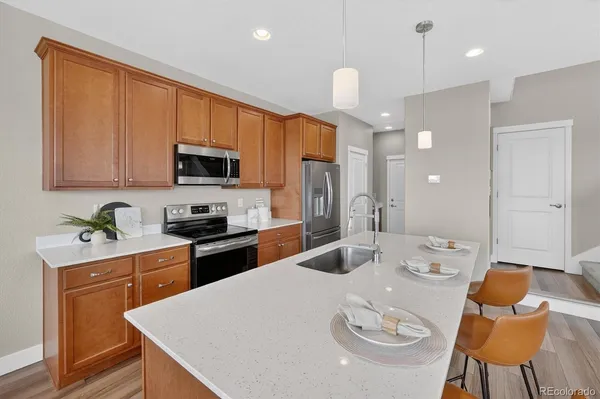 a kitchen with stainless steel appliances granite countertop a stove a sink a microwave a dining table and chairs with wooden floor
