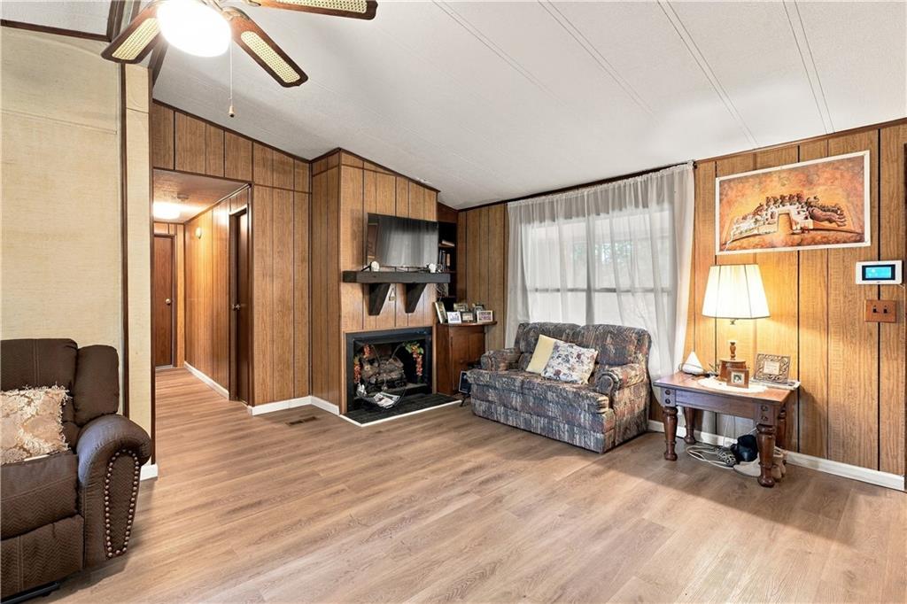 2 Kitetown Road Seale, AL 36875 - Photo 8 of 11 Wood-finish flooring, wood paneling, built-in fireplace with mantel, ceiling fan, and window with sheer coverings