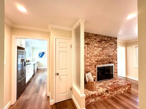 a view of a livingroom with wooden floor a fireplace and entryway