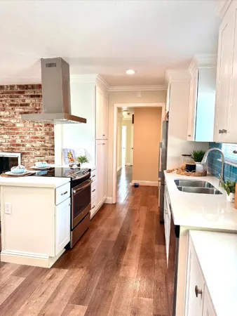 a kitchen with a sink stove and wooden floor