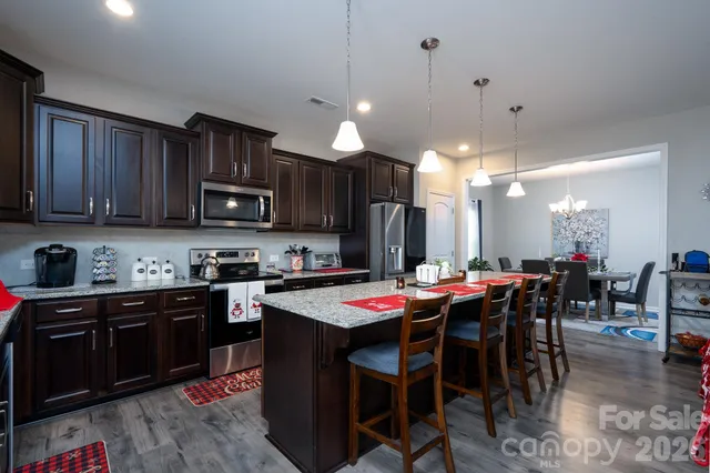 a kitchen with stainless steel appliances kitchen island granite countertop a dining table and chairs