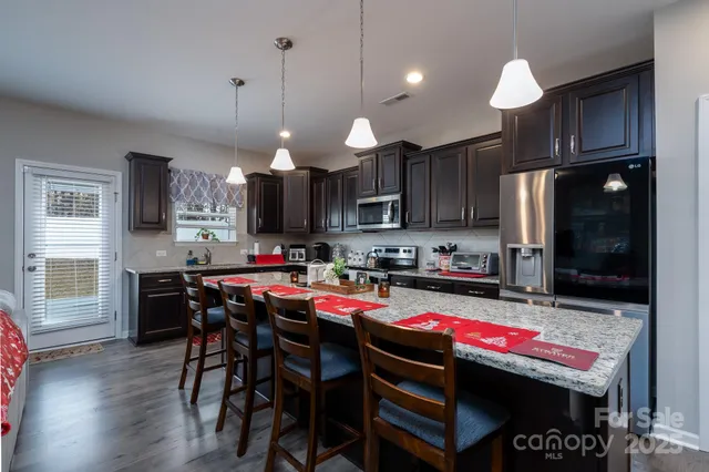 a kitchen with a stove a refrigerator and a dining table with wooden floor