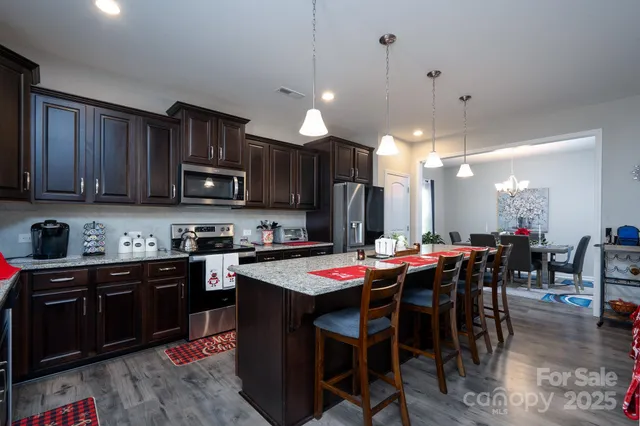 a kitchen with stainless steel appliances kitchen island granite countertop a dining table and chairs
