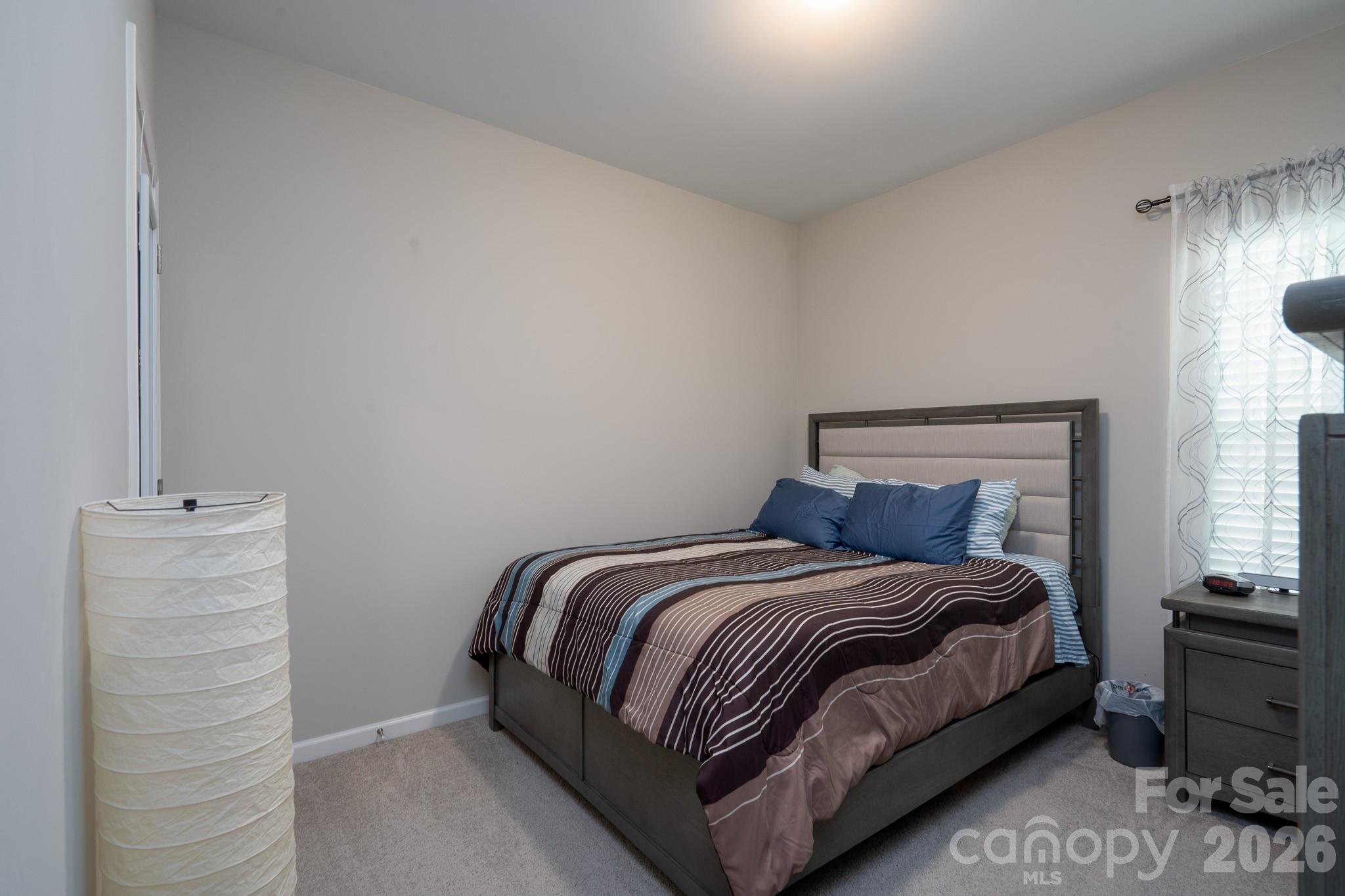 1772 Savannah Lane, Unit 19 Stanfield, NC 28163 - Photo 7 of 29 a bedroom with a bed lamp and a window