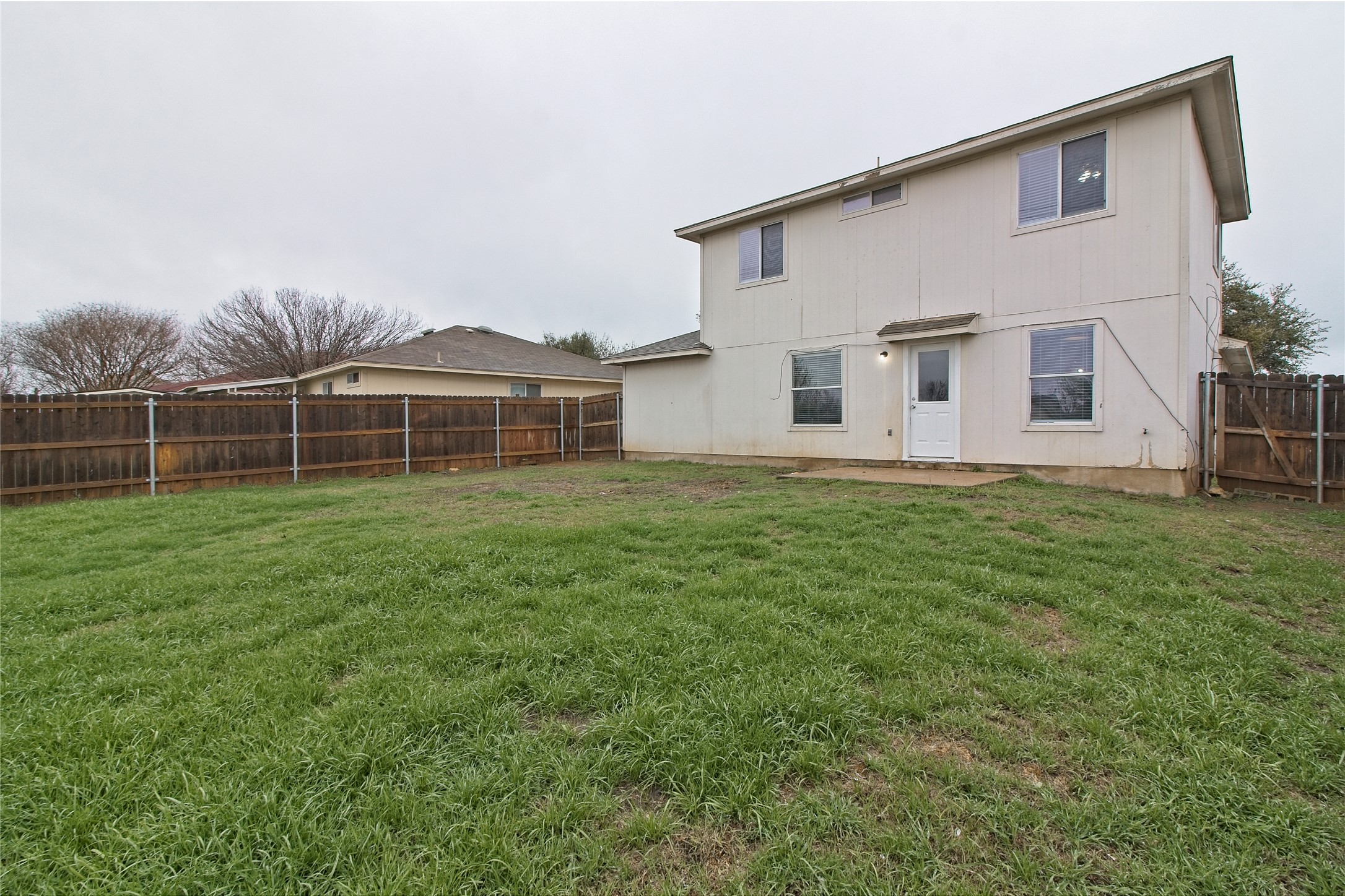 232 Brickyard Lane Jarrell, TX 76537 - Photo 28 of 31 A spacious backyard with mature trees, a privacy fence, and a simple patio.