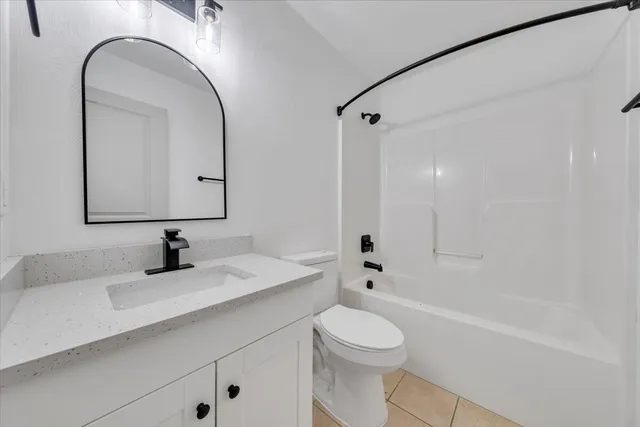 a bathroom with a bathtub shower sink vanity mirror and toilet