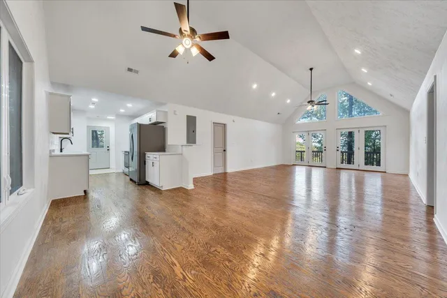 a view of an empty room with wooden floor and a kitchen