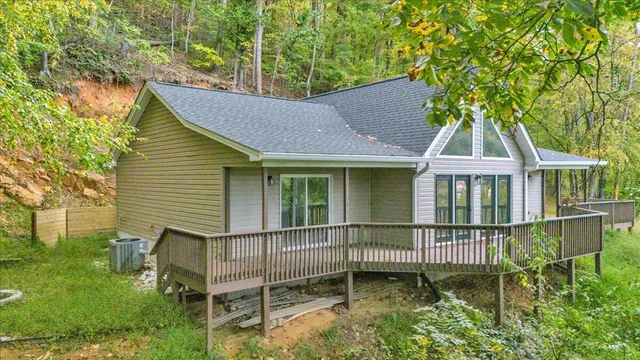 a view of a brick house with a small yard and a large tree
