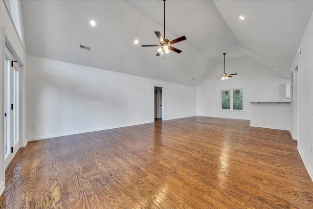 a view of empty room with wooden floor and ceiling fan