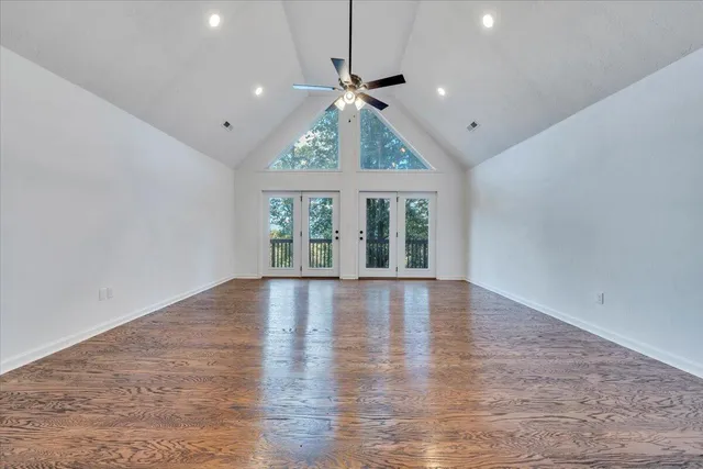 an empty room with wooden floor chandelier and windows