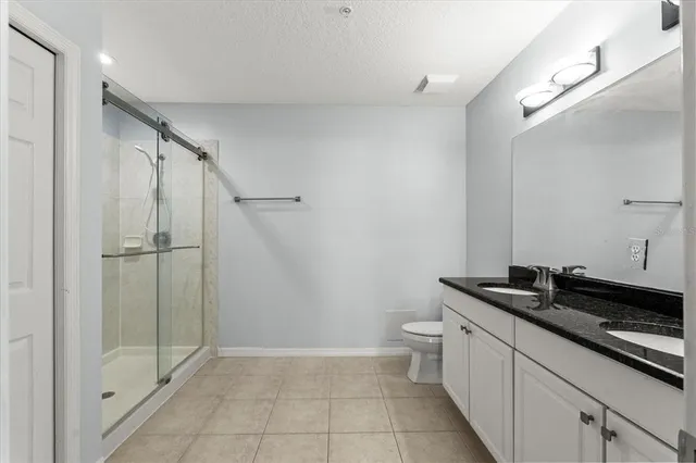 a bathroom with a granite countertop sink a toilet and shower