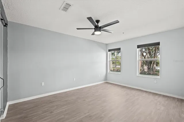 a view of an empty room with a window and wooden floor