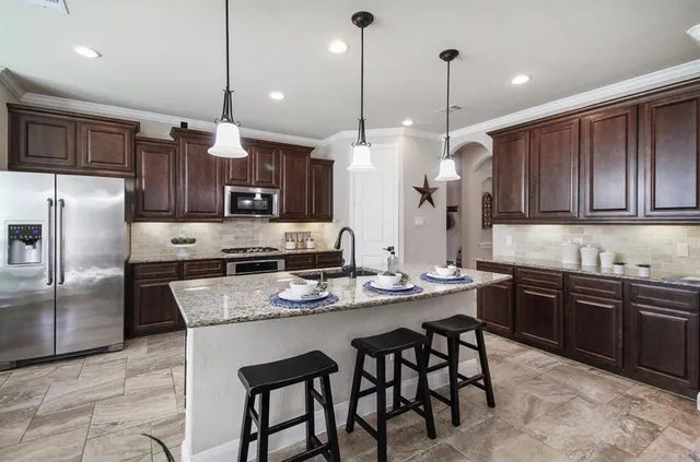 a kitchen with granite countertop wooden cabinets dining table and stainless steel appliances