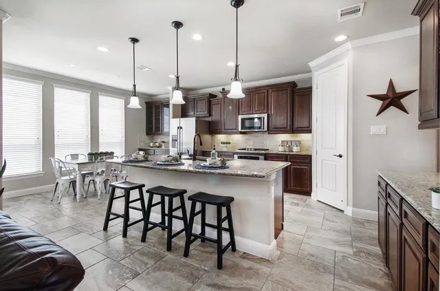 a kitchen with stainless steel appliances granite countertop a stove a sink a oven a dining table and chairs
