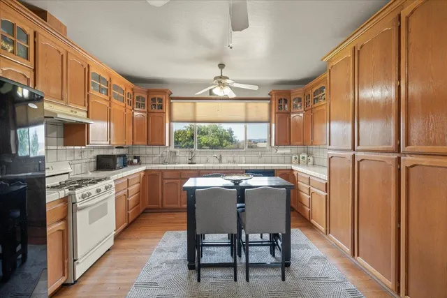 a kitchen with stainless steel appliances granite countertop a stove a sink dishwasher a refrigerator with white cabinets and wooden floor