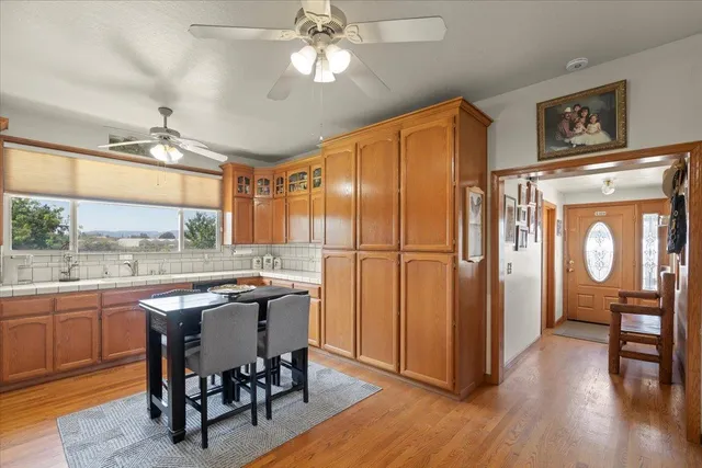 a kitchen with stainless steel appliances granite countertop a stove top oven a refrigerator a dining table and chairs with wooden floor