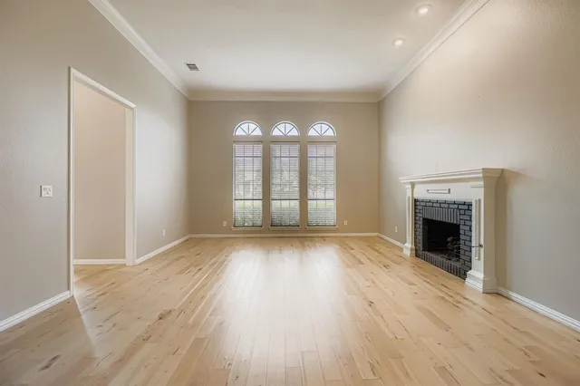 an empty room with wooden floor fireplace and windows