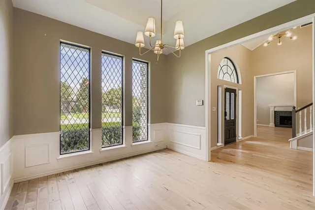a view of a big room with wooden floor chandelier and windows
