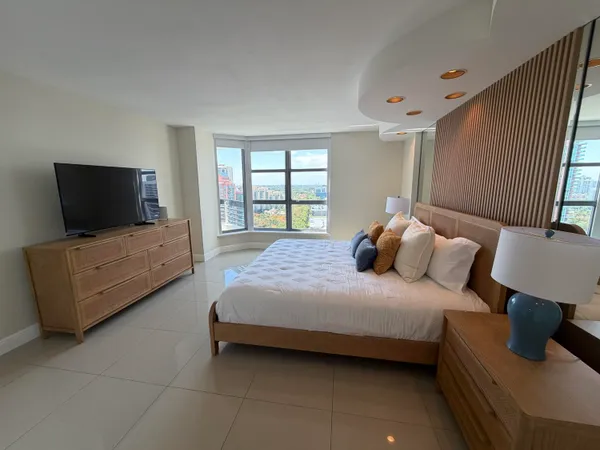 a bedroom with a bed and a flat tv screen on the dresser