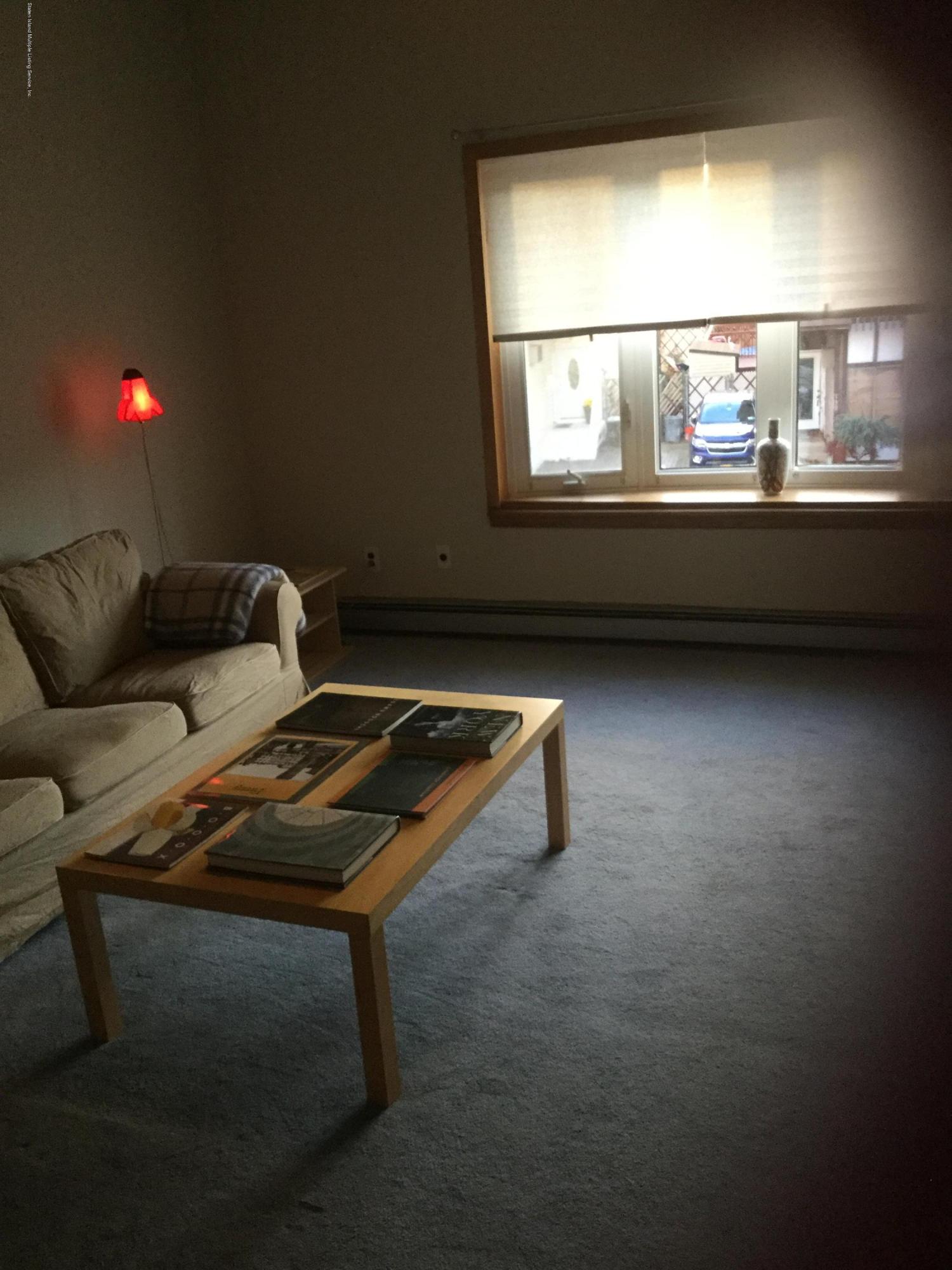 131 Green Valley Road Staten Island, NY 10312 - Photo 3 of 3 a living room with a couch and a floor to ceiling window
