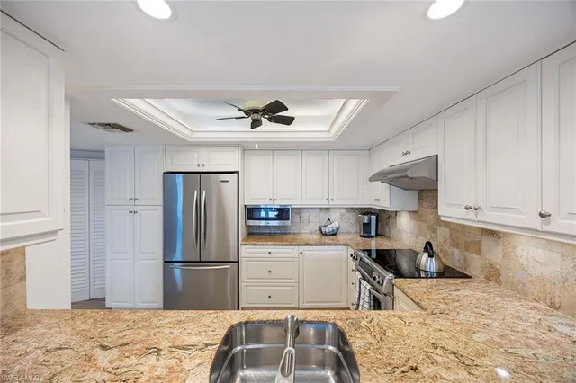 a kitchen with stainless steel appliances kitchen island granite countertop a refrigerator and a sink