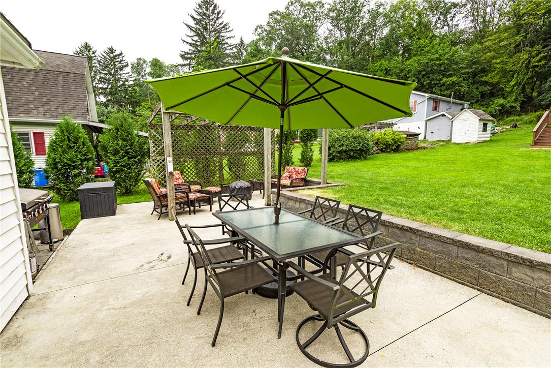 280 Oak Road Bangor, PA 18013 - Photo 5 of 52 A spacious concrete patio bordered by a low stone wall overlooks a lush green lawn.