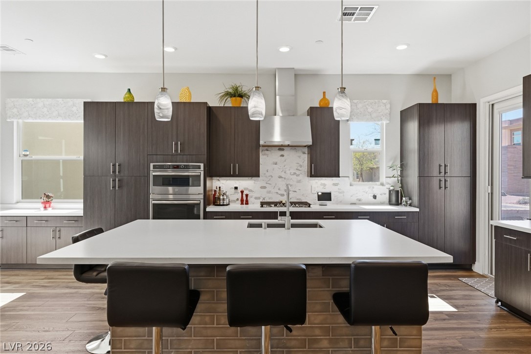 4246 Swift Street Las Vegas, NV 89135 - Photo 17 of 71 Kitchen featuring a kitchen breakfast bar, dark wood finish cabinetry, and an island with sink