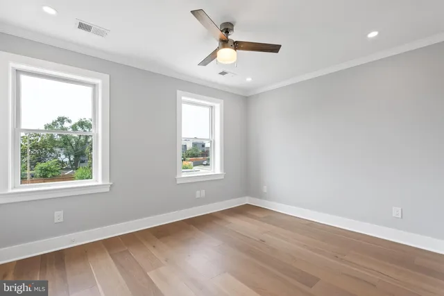 a view of empty room with wooden floor and fan