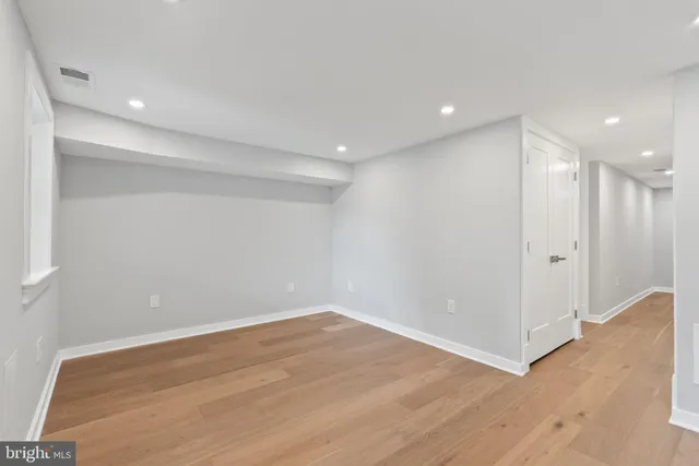 a view of empty room with window and wooden floor